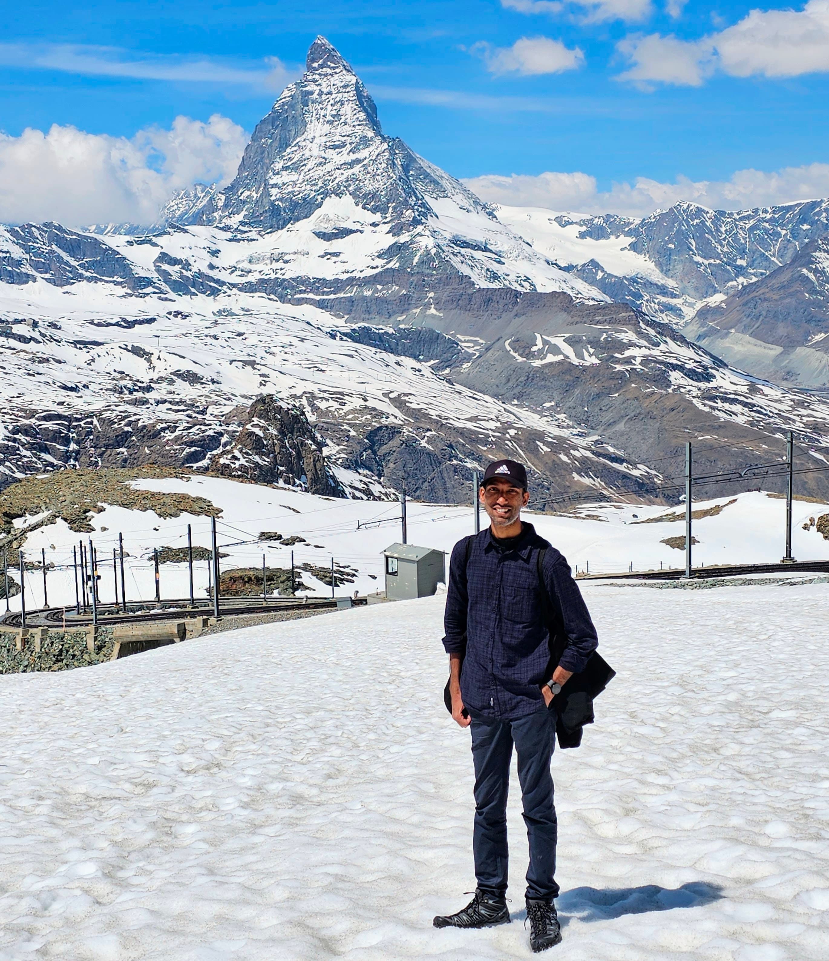 Danvendra Singh standing in the snow with a mountain behind him.